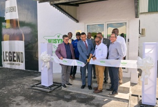 Prime Minister, Dr. the Most Hon. Andrew Holness (front row, second left), joins Director of Manufacturing and longest serving employee at Wisynco Group, Devon H. Reynolds (second right),  in cutting the ribbon to officially open the entity