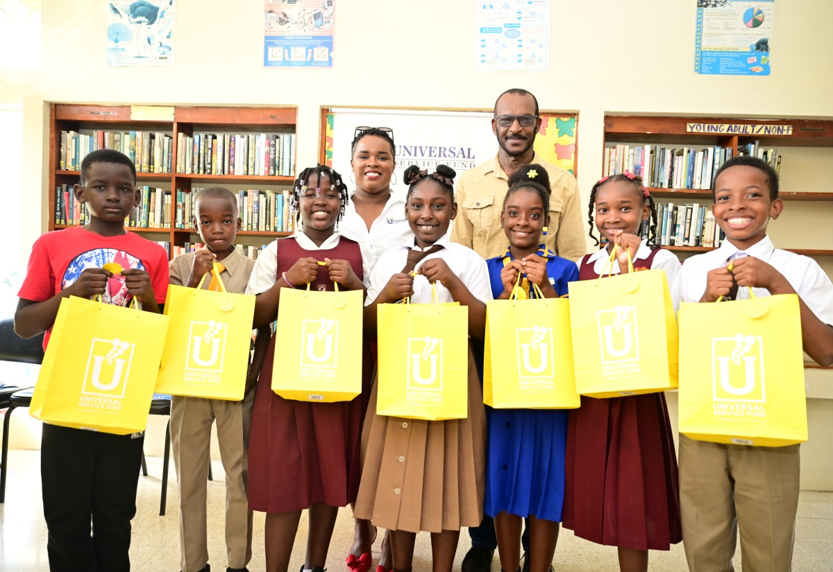 Marketing and Public Relations Manager at the Universal Service Fund (USF), Dana DeCardova-Denton, and Councillor for the Chapelton Division in Clarendon North Central, Hershell Brown, are pictured with seven of the 10 outstanding students from the constituency who excelled in the 2025 Primary Exit Profile (PEP) examinations. The students were presented with tablet computers under the USF’s Connect-A-Child Programme during a recent handover ceremony at the Chapelton Public Library in Clarendon.

