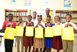 Marketing and Public Relations Manager at the Universal Service Fund (USF), Dana DeCardova-Denton, and Councillor for the Chapelton Division in Clarendon North Central, Hershell Brown, are pictured with seven of the 10 outstanding students from the constituency who excelled in the 2025 Primary Exit Profile (PEP) examinations. The students were presented with tablet computers under the USF’s Connect-A-Child Programme during a recent handover ceremony at the Chapelton Public Library in Clarendon.

