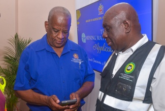 Minister of State in the Ministry of Agriculture, Fisheries and Mining, Hon. Franklin Witter (left), navigates the new Mining Matters app on his smartphone during the recent launch at the Wembley Centre of Excellence in Clarendon. Looking on is Clarendon Parish Manager for the Social Development Commission (SDC), Baldvin McKenzie.

