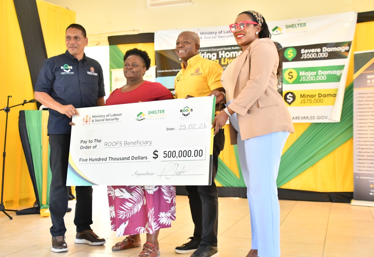 Minister of Labour and Social Security, Hon. Pearnel Charles Jr. (second right), presents a cheque to Hanover resident, Ena Campbell (second left), who lost her home during the passage of Hurricane Melissa last year. The occasion was the Hanover leg of the Restoration of Owner or Occupant Family Shelters (ROOFS) initiative handover ceremony, held at the Hanover Parish Church Hall in Lucea on Wednesday (February 25). Also participating are (from left), State Minister in the Labour Ministry, Hon. Donovan Williams, and Member of Parliament for Hanover Eastern, Andrea Purkiss. 

