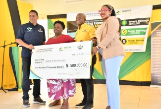 Minister of Labour and Social Security, Hon. Pearnel Charles Jr. (second right), presents a cheque to Hanover resident, Ena Campbell (second left), who lost her home during the passage of Hurricane Melissa last year. The occasion was the Hanover leg of the Restoration of Owner or Occupant Family Shelters (ROOFS) initiative handover ceremony, held at the Hanover Parish Church Hall in Lucea on Wednesday (February 25). Also participating are (from left), State Minister in the Labour Ministry, Hon. Donovan Williams, and Member of Parliament for Hanover Eastern, Andrea Purkiss. 

