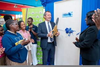 Director of the United Nations Educational, Scientific and Cultural Organization, Regional Office for the Caribbean, Eric Falt (fourth left), along with Director General for the Jamaica Library Service (JLS), Maureen Thompson (right), cut the ribbon to officially open the new Children’s Computer Lab at the St. James Parish Library as students from Chetwood Memorial Primary School look on.

