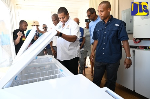 Minister of Agriculture, Fisheries and Mining, Hon. Floyd Green (third right), looks at the interior of a refrigerated unit inside the solar-powered community energy centre in Galleon, donated by the United Nations Development Programme (UNDP), which was handed over to the community in St. Elizabeth on Friday (Feb. 6). Also observing (from left) are Manager, St. Elizabeth Fish Sanctuary, Trysion Walters; State Minister in the Ministry, Hon. Franklin Witter; Chief Executive Officer, National Fisheries Authority (NFA), Dr. Gavin Bellamy; and Chief Executive Officer of STL Solar Limited, Daniel Schwapp.