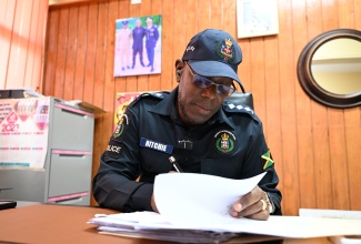 Commanding Officer for the Jamaica Constabulary Force (JCF) St. Thomas Division, Deputy Superintendent Rohan Ritchie, signs an event permit at the Morant Bay Police Station on February 25.
