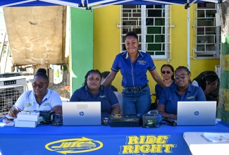 Jamaica Urban Transit Company (JUTC) Marketing and Sales Manager, Nathalia Palomino (standing), and her team at the SmartFare card activation drive held in Yallahs, St. Thomas, on Saturday (January 31). She is joined by (from left),  Revenue Agent, Lorraine Vassell; Kerri-Ann Hudson and Senior Revenue Agent, Sophia Edwards-Needham; and Business Development Officer, Chantal Rodgers (background right).

