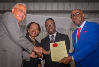 Justice and Constitutional Affairs Minister, Hon. Delroy Chuck (left), shakes hands with newly commissioned Justice of the Peace (JP) for St. Andrew, Adrian Atkinson (second right). He is joined by Principal Director, Justice Training Institute (JTI), Analia Wallace-Muir,  and Custos for St. Andrew, Ian Forbes (right), who presents Mr. Atkinson with the instrument of office. Occasion was the commissioning ceremony of 148 new JPs for St. Andrew on Sunday (February 23) at Jamaica College.

