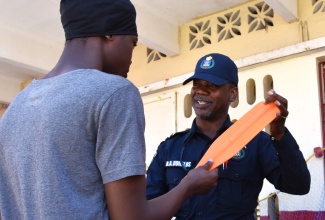 Representative of the Jamaica Constabulary Force’s (JCF) Marine Division, Corporal Derrick Donalds, explains the proper use of a rowboat paddle to the resident of Seaview Gardens, St. Andrew, during a Youth Empowerment Fair hosted in the community by the Social Development Commission (SDC) on Friday, February 20.

