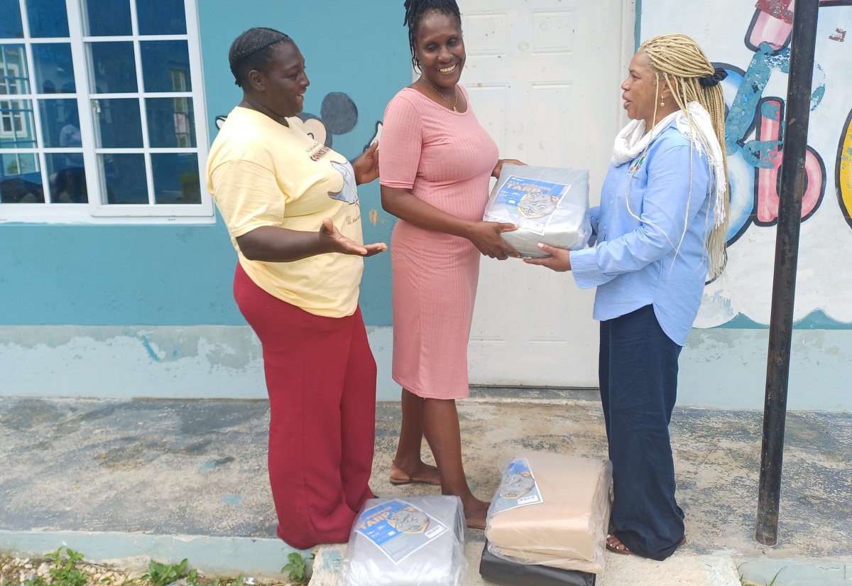 Founder and Executive Director of the United States (US)-based Pollyanna Project, Donna Moore-Stewart (right), hands over four tarpaulins to teacher at the Beeston Spring Basic School in Westmoreland, Annmarie Brown (centre), during a community outreach activity at the Beeston Spring Apostolic Church of God on Saturday (January 31). Sharing the moment is Events Coordinator at the church, Teenah Jamieson.  

