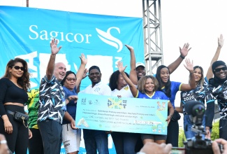 Minister of Education, Skills, Youth and Information, Senator Dr. the Hon. Dana Morris Dixon (front right) along with President and Chief Executive Officer of Sagicor Group Jamaica Limited, Christopher Zacca (front left), display a symbolic cheque for $152 million, at the 28th staging of the Sagicor Sigma Run in Kington on Sunday (February 15). Also present is State Minister in the Ministry of Education, Skills, Youth and Information, Hon. Rhoda Moy Crawford (third right, background) and other dignitaries.