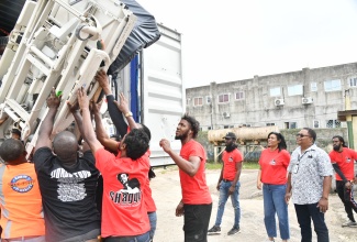 Chief Executive Officer of the Mandeville Regional Hospital, Alwyn Miller (right), and Kenisha Gibson (second right), representing the Shaggy Make a Difference Foundation and Project CURE, look on as beds donated to the hospital by the organisations are being removed from a truck. A total of 44 beds were handed over to the hospital in Manchester on Saturday (February 21).

