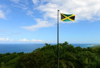 Flag of Jamaica waving against blue sky 