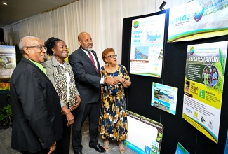 Special Envoy for Climate Change, Professor Dale Webber (left), looks at the exhibition of the various projects completed under the Government of Jamaica/Adaptation Fund Programme (GOJ/AFP), at the initiative’s close-out ceremony, held at the Summit in Kingston on Tuesday (March 24). He is joined by (from left) Programme Manager for the GOJ/AFP, Planning Institute of Jamaica (PIOJ), Shelia McDonald-Miller; Director General of the PIOJ, Dr. Wayne Henry and Member of the Programme’s Steering Committee, Eleanor Jones.  The programme, which was implemented in 2013, has achieved or surpassed its various objectives associated with increasing climate resilience in Jamaica.

