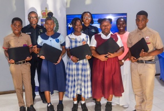 Some of the students who recently received laptops under the St. Catherine North Police Community Safety and Security Peace Ambassadors in School Initiative. They are (from left) Sheldon Walters, Britany Thompson, Elizabeth Cunningham, Ashley Jones, and Justine Stone. In the background (from left) are Territorial Officer in the St. Catherine North Police Division, Inspector Ishmael Williams; Assistant Police Youth Club Coordinator for the St. Catherine North Police Youth Club Council, Corporal Shantel Powell, who is also the LASCO/JCF Police Officer of the Year; and donor of the computers, Donique Sinclair-Chambers. Occasion was a recent handover ceremony, held at the Spanish Town Police Station in St. Catherine.