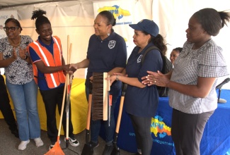 President of the Majesty Gardens Community Development Corporation, Jaheim Mitchell (second left), receives cleaning tools from Pan American Development Foundation Project Coordinator, Kimberly Seymour-Brown, at the Community Clean-up, E-Waste Drive, and the Waste Separation Initiative launch, held on Wednesday (March 18) in Majesty Gardens, St. Andrew. Sharing in the moment are (from left) Member of Parliament for St. Andrew Southwestern, Dr. Angela Brown-Burke; Pan American Development Foundation Project Coordinator, Stacy-Ann Barnes and Programme Assistant at the United States Embassy, Dahlia Davis-Gayle. The event was hosted by MPM Waste Management Limited, in partnership with the Pan American Development Foundation, in recognition of Global Recycling Day 2026. The day was observed under the theme ‘Don’t Think Waste – Think Opportunity’ and seeks to encourage individuals and organisations to recognise certain items as valuable resources rather than garbage.