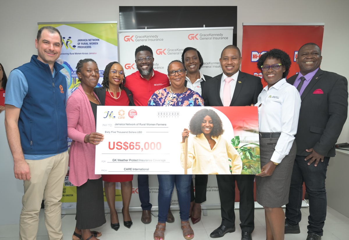 Minister of Agriculture, Fisheries and Mining, Hon. Floyd Green (third right), shares the moment as members of the Jamaica Network of Rural Women Producers (JNRWP) hold a symbolic cheque courtesy of CARE International during a handover ceremony for the Roots Resilience Parametric Insurance Programme held on Monday (March 9) at GraceKennedy (GK) General Insurance Company’s office in New Kingston. Also photographed (from left) are CARE International Caribbean Humanitarian Response Lead, Jonathan Arogeti; GK Group’s Head of General Insurance, Tammara Glaves-Hucey; GK General Insurance Client and Partner Services Manager, Orette Duncan; GK General Insurance Assistant General Manager for Client and Partner Services, Andrea Muir-Gibbs; JNRWP Executive Board Member, Marva Allen-Simms; and JNRWP Consultant, Christopher Chinapoo. The initiative will benefit 120 women producers, supported by a US$65,000 pledge from CARE International and a $900,000 commitment from Hi-Pro, and is facilitated through the GK Weather Protection Programme.

