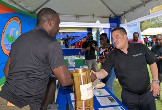 Minister of Water, Environment and Climate Change, Hon. Matthew Samuda (right), greets Meteorological Technician at the Meteorological Service of Jamaica,  Lerone Lynch, during a stop at the agency’s display booth at the World Water Day Exposition 2026 held on Friday (March 20), at the University of the West Indies (UWI), Mona Campus in St. Andrew.