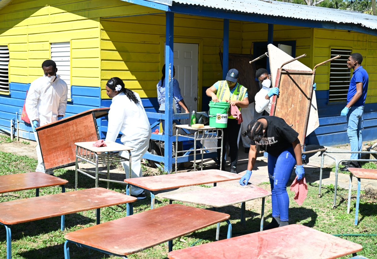 A joint team from the St. James Police Division’s Community Safety and Security Branch (CSSB) and the Spot Valley High School Police Youth Club clears and cleans school furniture during ‘Operation Clean-Up’ at the infant department of Lethe Primary and Infant School in Hanover on February 19.  

