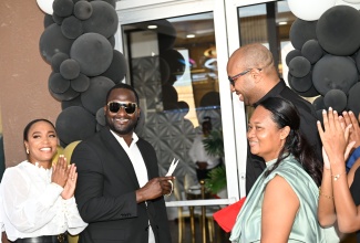 Minister of State in the Ministry of Industry, Investment and Commerce, Hon. Delano Seiveright (second right), looks on as Chief Executive Officer of Level 8 – Bakery, Dining and Gaming Lounge, Richard Cole, cuts the ribbon to mark the grand opening of the new establishment in Black River, St. Elizabeth, on Saturday (February 28). Sharing the moment are President of the St. Elizabeth Chamber of Commerce (Black River Chapter), Kadian Myers-Brown (left), and Level 8 co-owner, Taquilia Chin-Cole.

