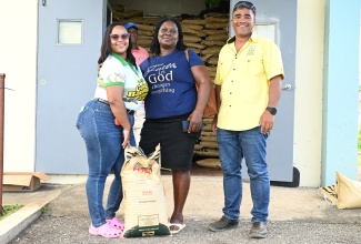 Banana Board’s Tiamhoi Moss (left) and Parish Manager of the Rural Agricultural Development Authority (RADA), St. Elizabeth, Mark Lee, hand over a bag of fertiliser to farmer, Fay Rodney, during the distribution and training session at the St. Elizabeth’s RADA Parish Office in Santa Cruz, on Thursday, March 12.

