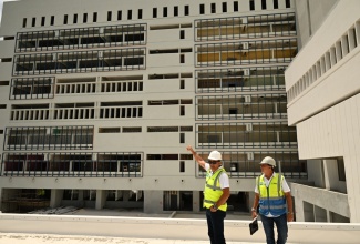 Minister of Health and Wellness, Dr. the Hon. Christopher Tufton (left), points to the progress of work on the Cornwall Regional Hospital Redevelopment Project, during a tour in July 2025. He was accompanied by Project Manager, Vivian Gordon.

