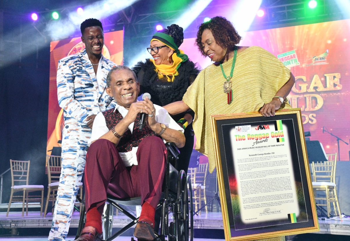 Minister of Culture, Gender, Entertainment and Sport, Hon. Olivia Grange (right), presents the Jamaica Music Museum Hall of Fame citation to veteran reggae artiste Ken Boothe (left), during the induction ceremony on Friday (February 27) at the National Area in Kingston. Sharing in the moment (background, from left) are singer and songwriter, Romaine Virgo and veteran reggae artiste, Marcia Griffiths.


