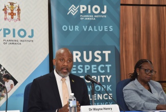 Director General, Planning Institute of Jamaica (PIOJ), Dr. Wayne Henry, responds to a question during the PIOJ’s quarterly hybrid media briefing on the performance of the economy for the period October to December 2025 on Tuesday (March 3).  At right is Deputy Director General, PIOJ, Claire Bernard.

