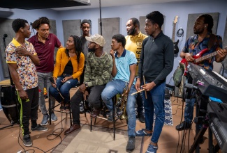 Reggae Music Director, Tourism Entertainment Academy, Othneil “Taddy P” Campbell (second left), in conversation with members of the Reggae Band during one of their rehearsal sessions.

