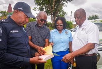 Minister of State, Ministry of Agriculture, Fisheries and Mining, Hon. Franklin Witter (right), observes as Chief Executive Officer, Rural Agricultural Development Authority (RADA), Garnet Edmondson (second left), highlights the contents of the receipt book used to document the sale and transport of livestock and produce. Also looking on are Sub-Officer in charge of Area 5, Detective Inspector Robert Robinson (left); and Acting Director, Praedial Larceny Prevention Coordination Branch, Kalecia Hall. Occasion was the Jamaica Constabulary Force’s (JCF) Praedial Larceny Sensitisation Session held at Linstead Anglican Church in St. Catherine on Thursday (Feb. 26).