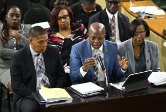 Minster of Labour and Social Security, Hon. Pearnel Charles Jr. (centre), responds to a question during the meeting of the Standing Finance Committee at Gordon House on Friday (March 6). He is flanked by Minister of State, Donovan Williams and Acting Permanent Secretary, Dione Jennings.
