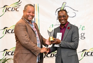 Director of Arts Development and Training at the Jamaica Cultural Development Commission (JCDC), Andrew Brodber (left), presents a trophy and cash award to the Overall Best Writer in the 2023 Jamaica Creative Writing Competition, Clyde Bowen, at an awards ceremony and launch of the Jamaica Creative Writing Exhibition, at the Summit in Kingston. 


