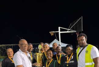 Senator and Councillor for the Montego Bay North Eastern Division, Charles Sinclair (front left), and Community Liaison Officer for the Social Development Commission, Warren Morle (right), present the championship trophy and winning cash prize to the victorious Pelle Drive team following their triumph in the final of the third staging of the Flankers Night Out Netball Competition on Sunday, March 1, 2026.

