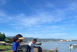 National Solid Waste Management Authority (NSWMA) Community Relations Manager, Sharnon Williams (left), joins WPM Waste Management Limited team member, Andrew Hart, in clearing discarded waste from Fisherman’s Beach in St. James during International Coastal Clean‑up (ICC) Day activities.


