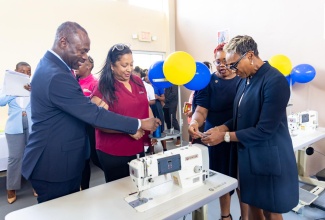State Minister in the Ministry of National Security and Peace, Hon. Juliet Cuthbert-Flynn (right), threads a sewing machine in the new sewing lab at the South Camp Juvenile Correctional and Remand Centre in Kingston, through assistance from Chief Technical Director in the Ministry, Shauna Trowers. Looking on (from left) are Commissioner of Corrections, Department of Correctional Services (DCS), Brigadier (Ret’d) Radgh Mason, and Chief Executive Officer, Digicel Foundation, Charmaine Daniels.

