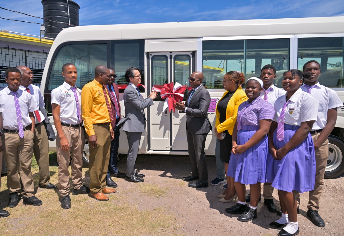 Minister of Labour and Social Security and Member of Parliament for Clarendon South Eastern, Hon. Pearnel Charles Jr. (sixth right), and Ambassador-designate of Japan to Jamaica, His Excellency Kohei Maruyama (sixth left), cut the ribbon to officially hand over a new school bus to Bustamante High School on Thursday (March 5) at the institution’s grounds in Lionel Town, Clarendon. Joining the moment are Principal, Bustamante High School, Wayne Evans (fourth from left); Regional Director, Region 7, Ministry of Education and Youth, Barrington Richardson (fifth from left); Executive Director of the National Education Trust (NET), Latoya Harris Ghartey (fifth from right); other stakeholders and students. The vehicle was donated through the Government of Japan’s Grant Assistance for Grassroots Human Security Projects to improve transportation, safety and access to school activities for students and staff.

