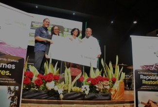 Minister of Labour and Social Security, Hon. Pearnel Charles Jr. (right), presents a grant cheque to Restoration of Owner or Occupant Family Shelters (ROOFS) Programme beneficiary, Julia Shaw (second right), during the Trelawny leg of the initiative’s handover ceremony, held at Abundant Life Ministries Church in Bounty Hall on March 11. Looking on are: State Minister, Hon. Donovan Williams, and State Minister in the Ministry of Tourism and Member of Parliament for Trelawny Northern, Hon. Tova Hamilton.
