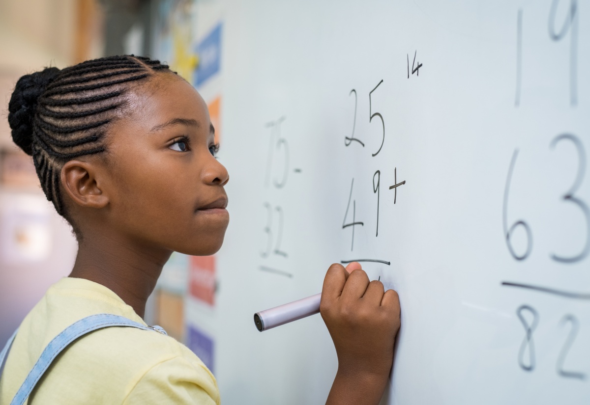81.	Schoolgirl thinking while solving a math equation on the board.