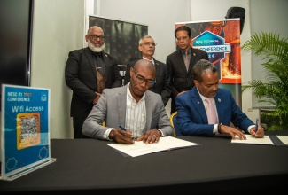 Dean of the Faculty of Applied Sciences, Engineering and Technology at the College of Agriculture, Science and Education (CASE) in Portland, Delford Morgan (left, seated), and President of the National Energy Skills Centre (NESC) Technical Institute in Trinidad and Tobago, Kern Dass (right, seated), affix their signatures to a study abroad agreement during NESC’s inaugural Technical and Vocational Education and Training (TVET) Conference, held on  April 23, in the twin‑island republic
Observing the signing are Trinidadian Cabinet Members (from left): Minister of Energy and Energy Industries, Ernesto R. Kesar; Minister of Tertiary Education and Skills Training, Professor Prakash Persad; and Minister of Education, Dr. Michael Dowlath.