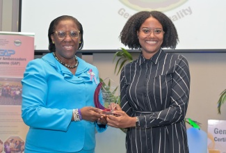 Principal Director , Bureau of Gender Affairs (BGA), Sharon Coburn Robinson (left), presents Policy Analyst in the Office of the Prime Minister, Christine‑Ann McKen (right), with an award in recognition of Outstanding Performance and Most Active Gender Focal Point (Established), during the recent Gender Mainstreaming Certification and Recertification Ceremony held at the AC Hotel by Marriott, Kingston.
