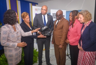 State Minister in the Ministry of Industry, Investment and Commerce, Hon. Delano Seiveright (left); Executive Director of the Bureau of Standards Jamaica (BSJ), Dr. Velton Gooden, and 

Chief Executive Officer of the CARICOM Regional Organization for Standards and Quality, Dr. Sharonmae Smith Walker, examine a helmet at the launch of the BSJ Motorcycle Helmet standard - JS 374:2025 Jamaica Standard Specification – Protective Helmets for Road Users - on March 31 at the Jamaica Business Development Corporation (JBDC) Incubator and Resource Centre in Kingston.