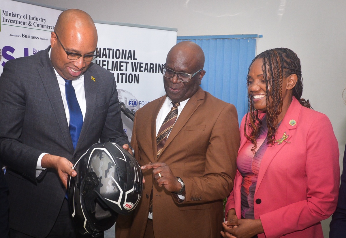 State Minister in the Ministry of Industry, Investment and Commerce, Hon. Delano Seiveright (left); Executive Director of the Bureau of Standards Jamaica (BSJ), Dr. Velton Gooden; and Chief Executive Officer of the CARICOM Regional Organisation for Standards and Quality (CROSQ), Dr. Sharonmae Smith Walker, examine a helmet during the launch of the BSJ