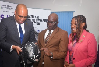 State Minister in the Ministry of Industry, Investment and Commerce, Hon. Delano Seiveright (left); Executive Director of the Bureau of Standards Jamaica (BSJ), Dr. Velton Gooden; and Chief Executive Officer of the CARICOM Regional Organisation for Standards and Quality (CROSQ), Dr. Sharonmae Smith Walker, examine a helmet during the launch of the BSJ