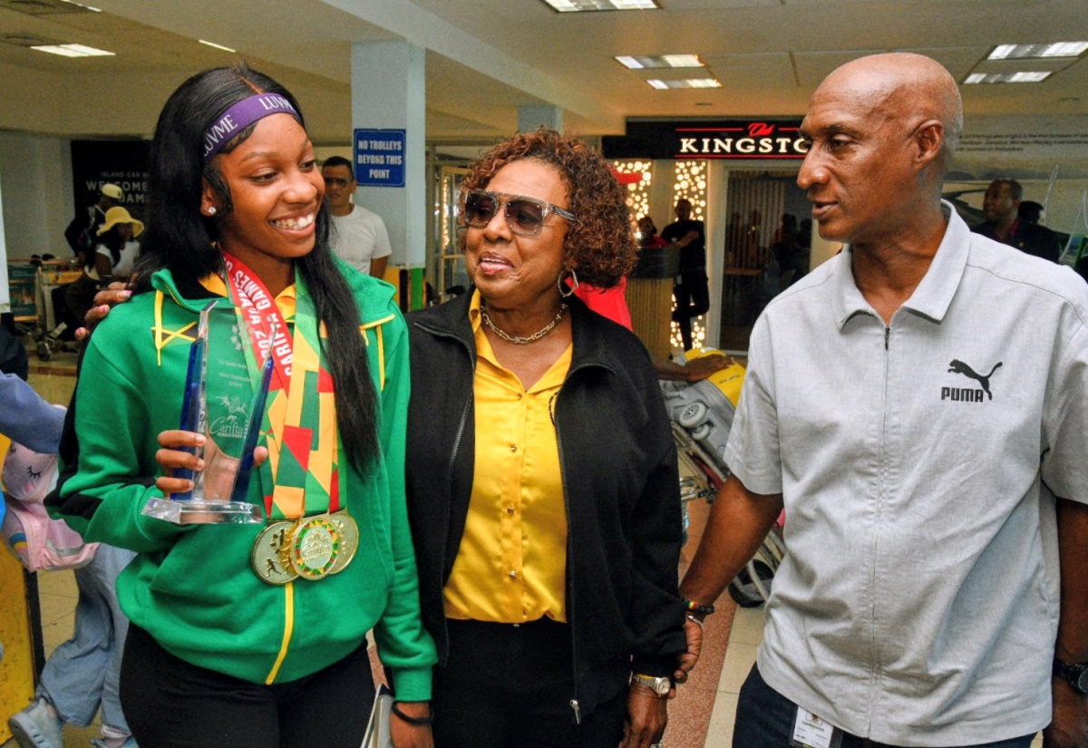 Minister of Culture, Gender, Entertainment and Sport, Hon. Olivia Grange (centre), and President, Jamaica Amateur Athletics Association (JAAA), Garth Gayle (right), engage with winner of the Austin Sealy Award at the 2026 CARIFTA Games, Shanoya Douglas. The Minister was at the Norman Manley International Airport on Tuesday (April 7) to welcome home the junior track and field athletes, which again topped the CARIFTA medal table with 71 medals.
