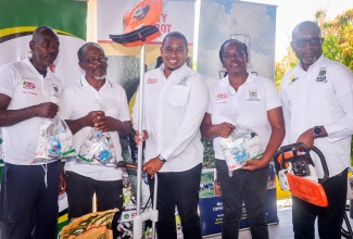 Minister of Agriculture, Fisheries and Mining, Hon. Floyd Green (third left), and Chief Executive Officer of the Rural Agricultural Development Authority (RADA), Garnet Edmondson (right), with farmers at a graduation ceremony for 50 cocoa farmers who successfully completed training in Cocoa Frosty Pod Disease Management, held on April 1 at the Denbigh Showground in Clarendon. The farmers received seeds and agricultural tools from the Ministry. They are (from left) Herbert Freckleton, Andrae Forrester, and Pauline Bryce.