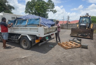 Workers remove bulky waste during an Earth Day clean-up exercise at the Old Police Station in May Pen on April 22.
