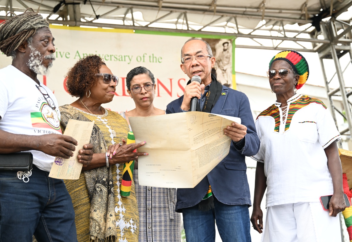 Deputy Prime Minister and Minister of National Security, Hon. Dr. Horace Chang (second right), and Minister of Culture, Gender, Entertainment and Sport, Hon. Olivia Grange (second left), examine certificates of title for lands transferred to the Rastafari Coral Gardens Benevolent Society (RCGBS). The presentation took place during the annual Commemorative Anniversary of the Coral Gardens Atrocity Against Rastafari, held in Albion, St. James, on Good Friday (April 3). Also pictured (from left) are RCGBS member, Lewis Brown (Ras Brown); Chief Executive Officer of the National Land Agency (NLA) and Commissioner of Lands, Cheriese Walcott; and RCGBS member, Pamela Rowe-Williams (Sistha Nanny).