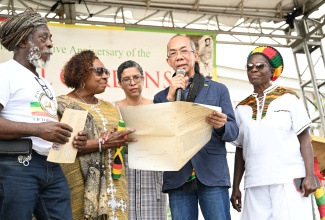Deputy Prime Minister and Minister of National Security, Hon. Dr. Horace Chang (second right), and Minister of Culture, Gender, Entertainment and Sport, Hon. Olivia Grange (second left), examine certificates of title for lands transferred to the Rastafari Coral Gardens Benevolent Society (RCGBS). The presentation took place during the annual Commemorative Anniversary of the Coral Gardens Atrocity Against Rastafari, held in Albion, St. James, on Good Friday (April 3). Also pictured (from left) are RCGBS member, Lewis Brown (Ras Brown); Chief Executive Officer of the National Land Agency (NLA) and Commissioner of Lands, Cheriese Walcott; and RCGBS member, Pamela Rowe-Williams (Sistha Nanny).