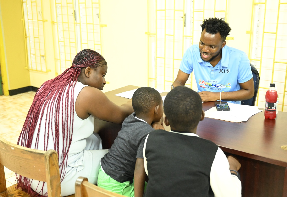 President of Junior Chamber International (JCI) Jamaica, Marklon Bedward, assists a family during the JCI Jamaica Autism Expo held recently at Hopewell High School in Hanover.
