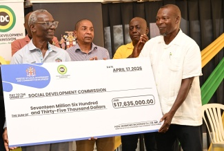 Minister of Local Government and Community Development, Hon. Desmond McKenzie (left), makes a symbolic handover of a $17.6 million cheque under the Government’s Community Church Clean-Up and Restoration Initiative that was accepted by Rev. Othniel Watson (right) of the Middle Quarters New Testament Church of God, during the initiative’s handover ceremony on Friday (April 17) in St. Elizabeth. Looking on are (from left) State Minister in the Ministry of Local Government and Community Development, Hon. Delroy Williams, and Executive Director of National Solid Waste Management Authority (NSWMA), Audley Gordon.