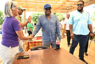 Tourism Minister, Hon. Edmund Bartlett, greets Sandy Tatham of Blue Marlin Villas during his visit to Jack Sprat Restaurant in Treasure Beach, St. Elizabeth, on the second day of the South Coast Confidence Tour on Friday (April 24). Looking on is Tourism Product Development Company (TPDCo) Destination Manager for the South Coast, Jonathan Bamidele (right).